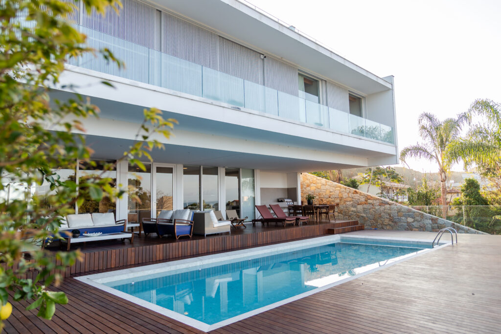 Fachada dos fundos com piscina, deck de madeira e esquadrias de vidro de correr Weiku