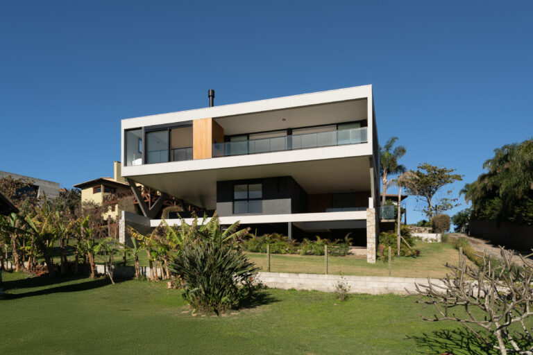 Fachada de residência contemporânea com volumes brancos em balanço, guarda-corpo de vidro e esquadrias Weiku