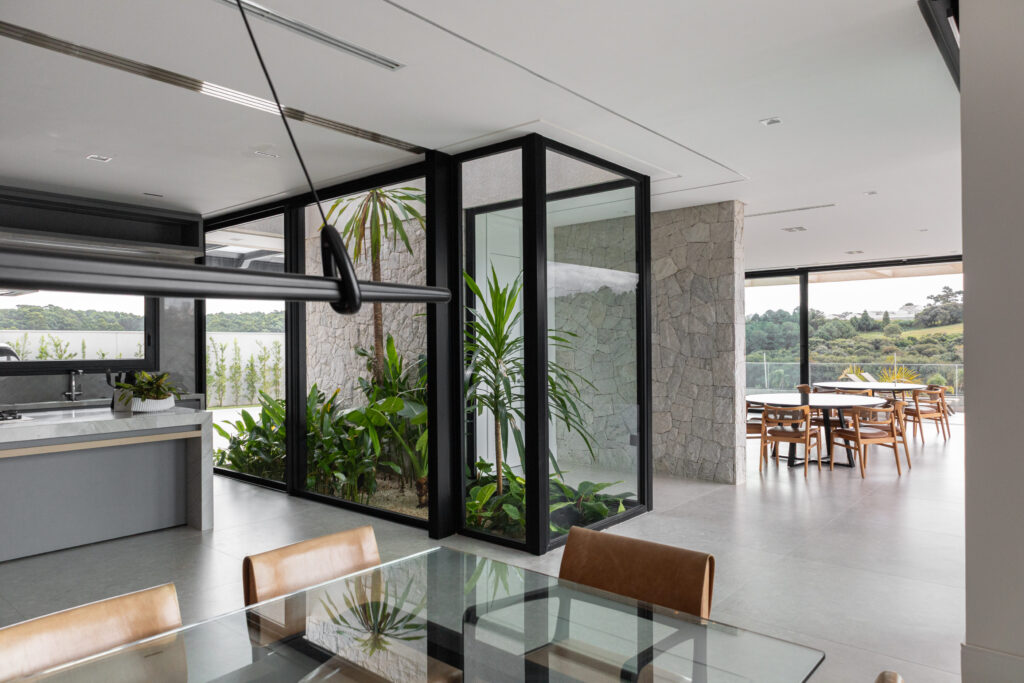 Sala de jantar com jardim de inverno envidraçado em esquadria Weiku de perfil preto