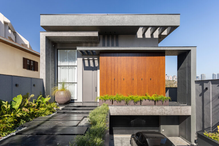 Fachada frontal de residência contemporânea em concreto e painel de madeira, com esquadrias Weiku