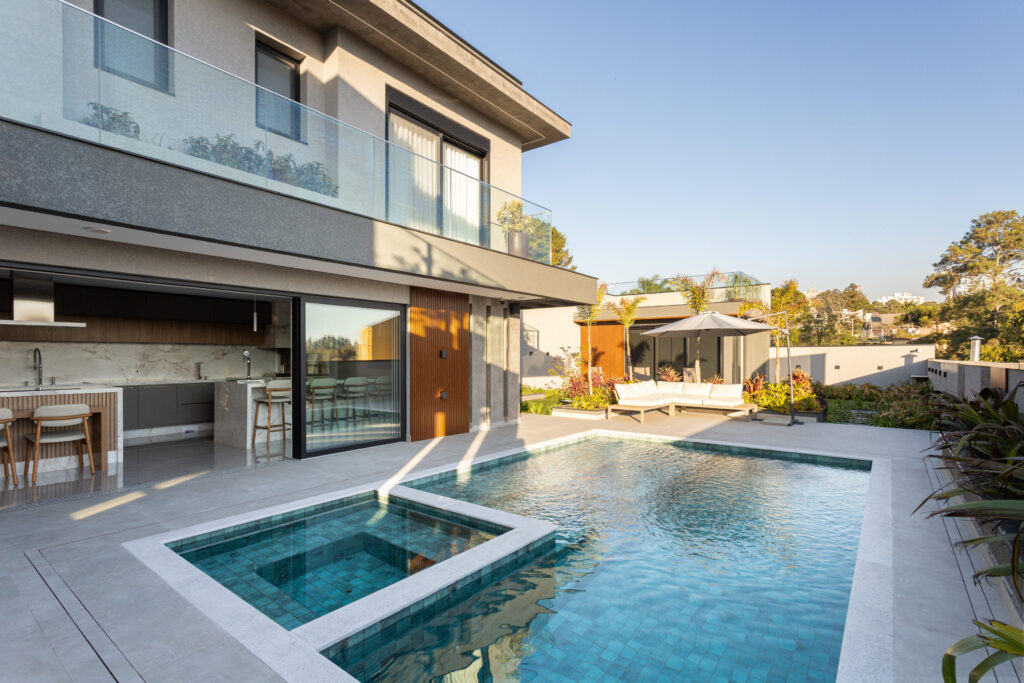 Fachada dos fundos com piscina e spa, guarda-corpo de vidro e esquadrias de vidro de correr Weiku