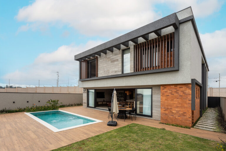Fachada dos fundos de residência contemporânea em tijolo e concreto, com brise de madeira, piscina e esquadrias de vidro Weiku