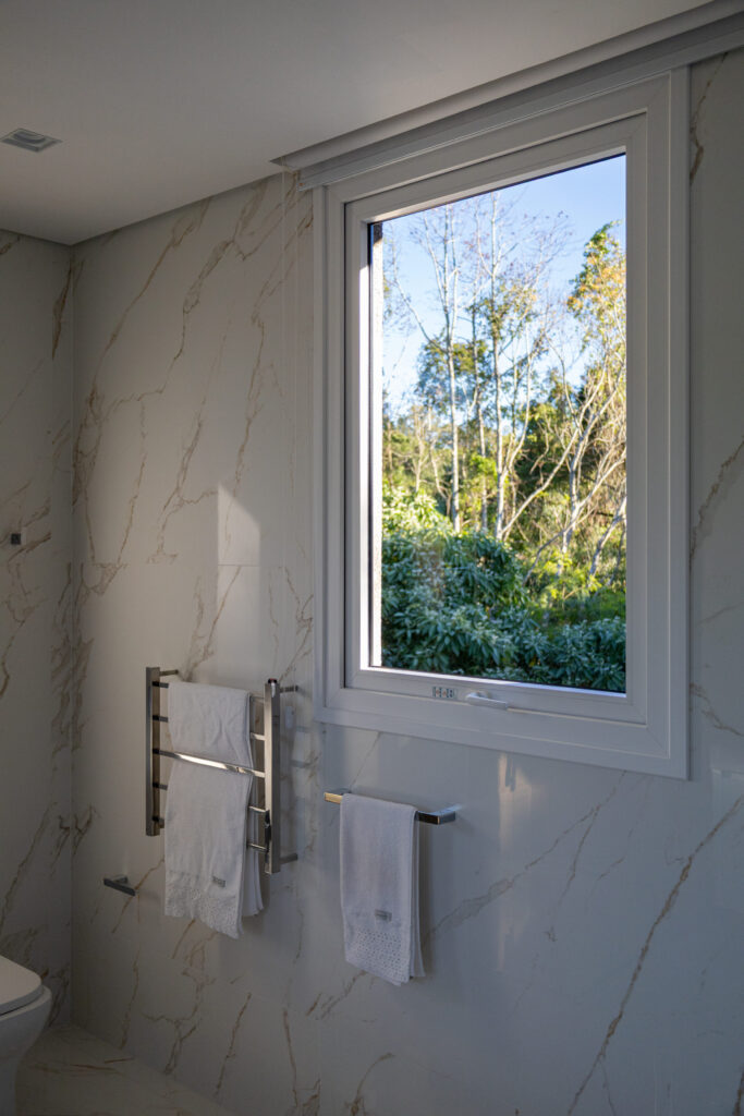 Banheiro em mármore com janela de vidro Weiku de perfil branco e vista para o verde