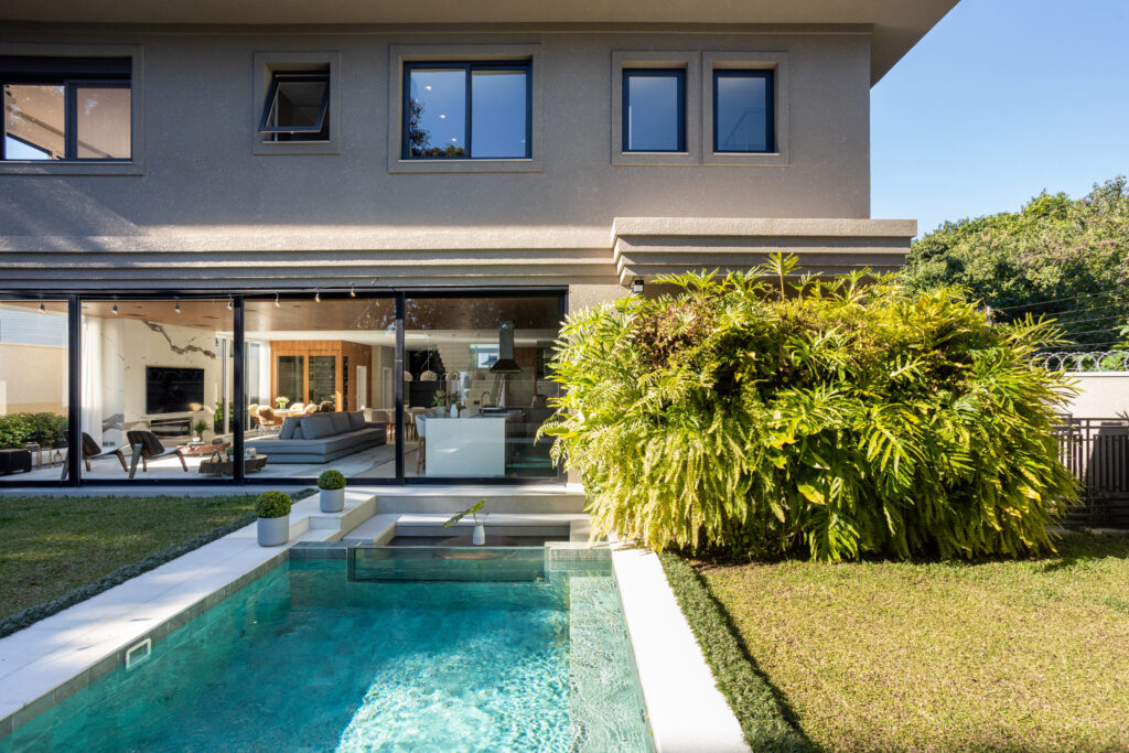 Fachada dos fundos de residência contemporânea com piscina e amplas esquadrias de vidro de correr Weiku