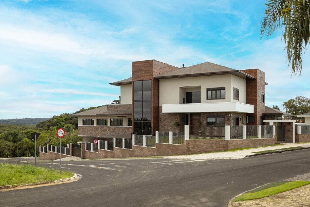 Fachada de residência contemporânea revestida em tijolinho, com pano de vidro de pé-direito duplo e esquadrias Weiku