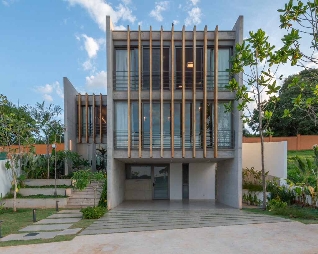 Fachada de residência em concreto aparente com brises verticais de madeira e panos de vidro Weiku nos dois pavimentos superiores