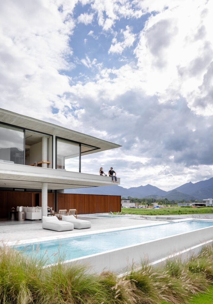 Lajes de concreto em balanço com panos de vidro Weiku de perfil preto sobre piscina em raia, com vista para as montanhas