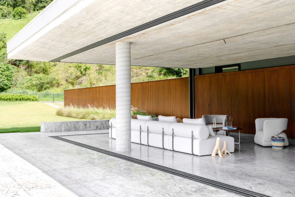 Living aberto para o jardim com portas de vidro de correr Weiku recolhidas, painel ripado de madeira e pilar de concreto