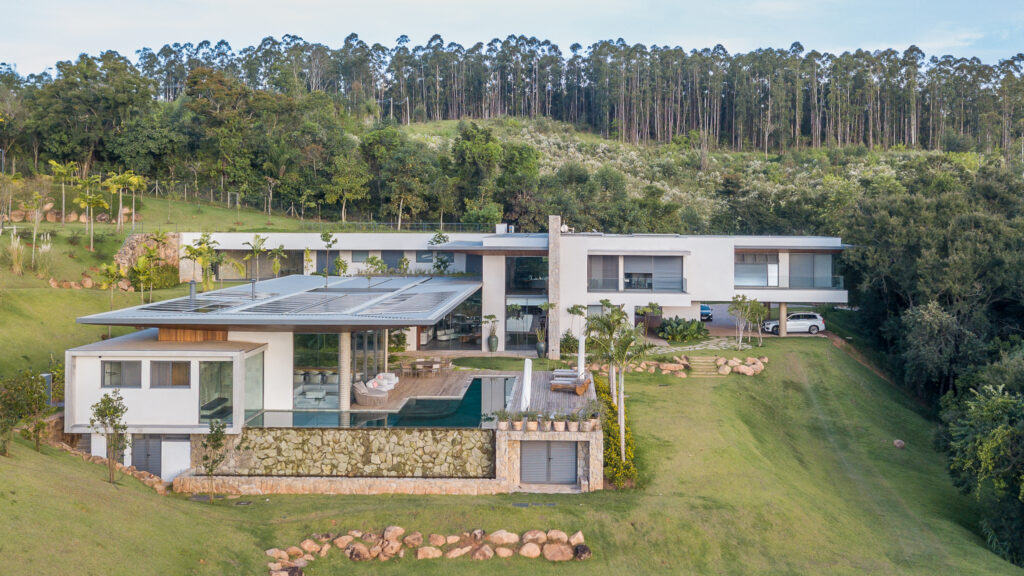 Vista aérea de residência contemporânea de campo em encosta, com piscina de borda infinita, muro de pedra e esquadrias de vidro Weiku