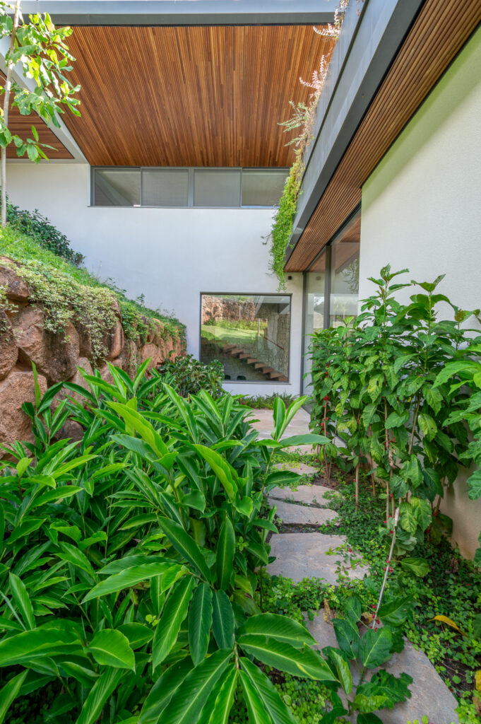 Jardim lateral com caminho de pedra, beiral de madeira e janelas de vidro Weiku de perfil escuro