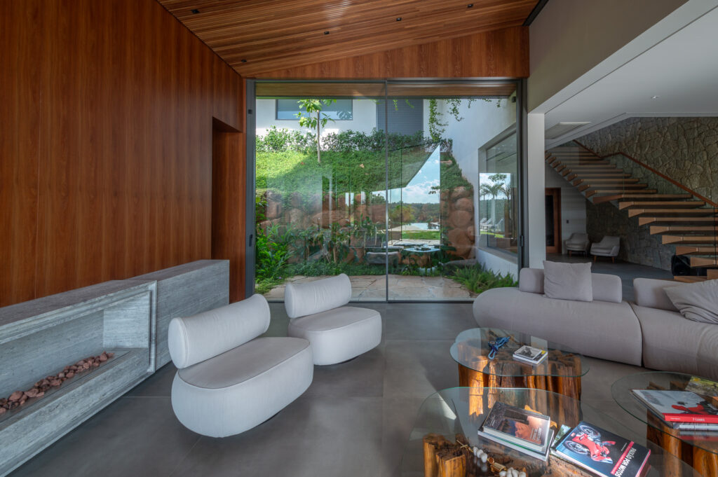 Living com painel de madeira e porta de vidro Weiku de piso a teto abrindo para o jardim interno