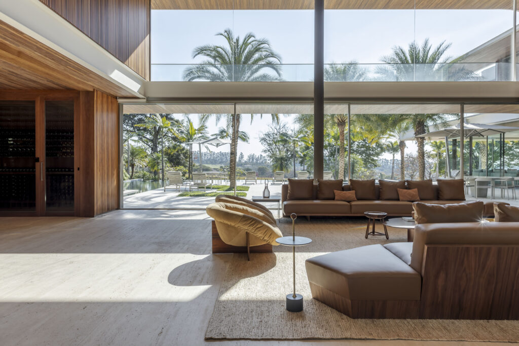 Living com piso de travertino e panos de vidro Weiku de grande altura voltados para a piscina e as palmeiras