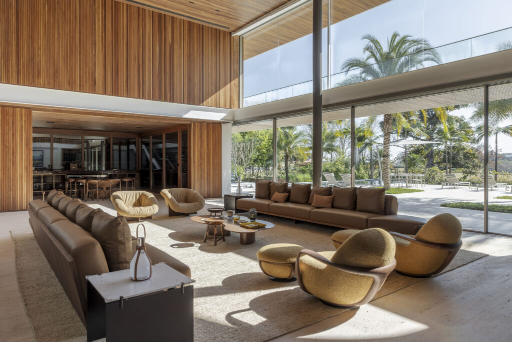Living de pé-direito duplo com painéis de madeira ripada e panos de vidro Weiku de piso a teto abertos para o jardim