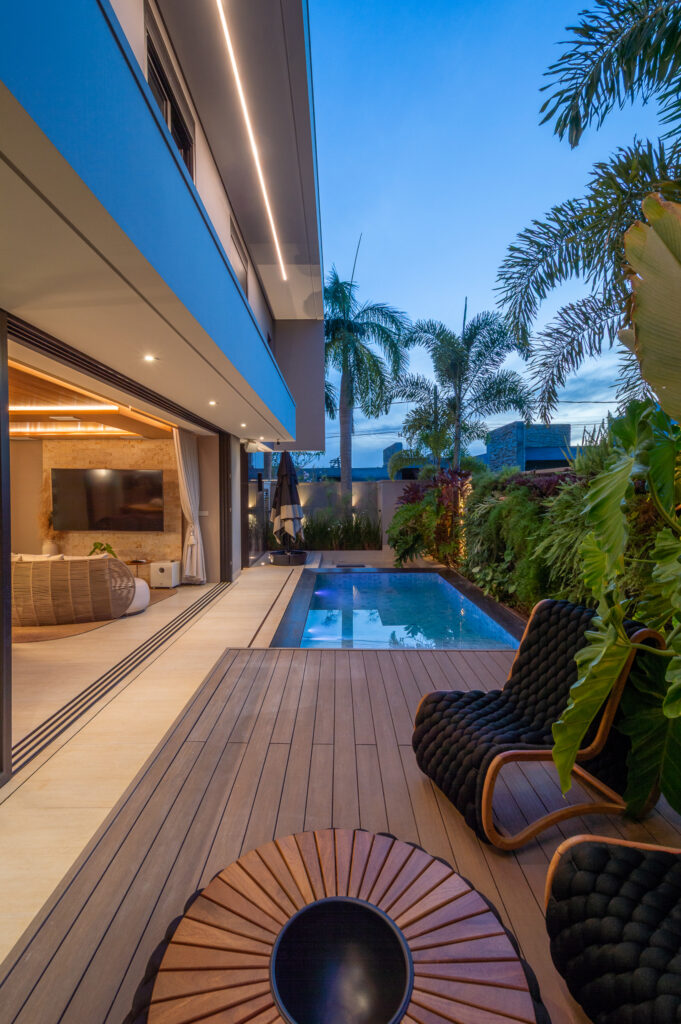 Deck de madeira e piscina junto a jardim vertical, ao lado de portas de vidro de correr Weiku abertas para o estar