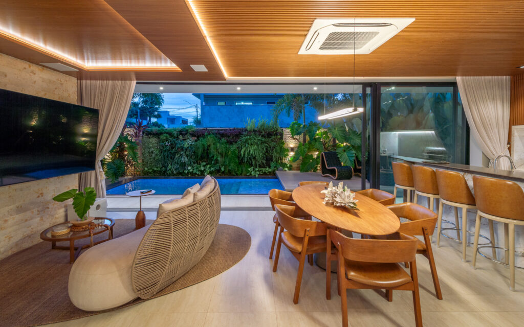 Estar e jantar do espaço gourmet com portas de vidro de correr Weiku abertas para a piscina e o jardim vertical