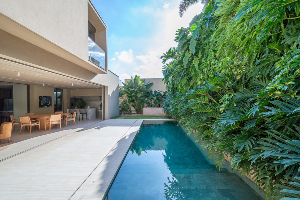 Piscina em raia ao lado de jardim vertical, com portas de vidro de correr Weiku totalmente abertas para a varanda e a sala de jantar