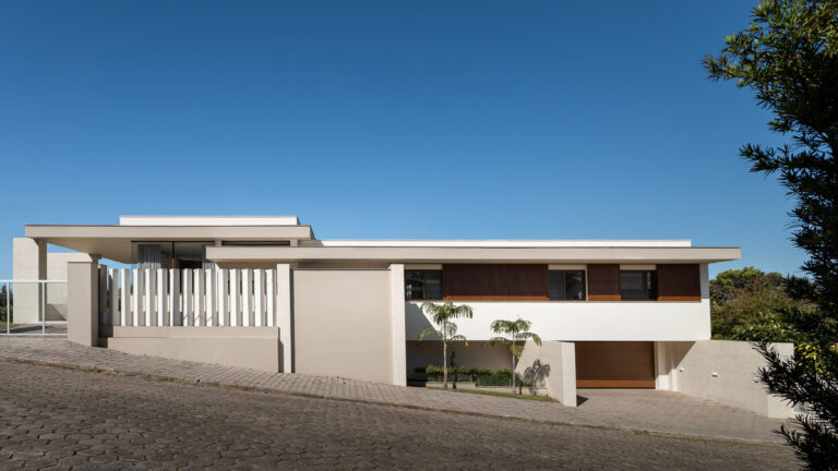 Fachada lateral de residência contemporânea com lajes planas em balanço, brises de madeira e esquadrias Weiku em terreno em declive
