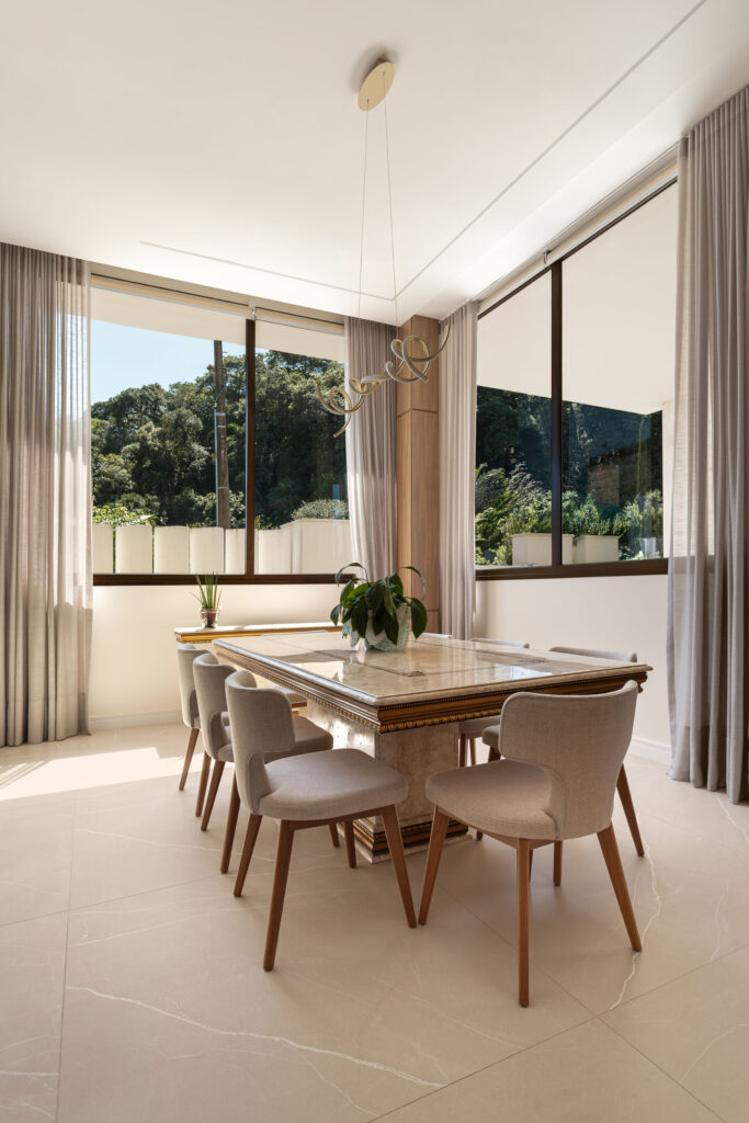 Sala de jantar com janelas de vidro Weiku de perfil escuro em canto, emoldurando o verde