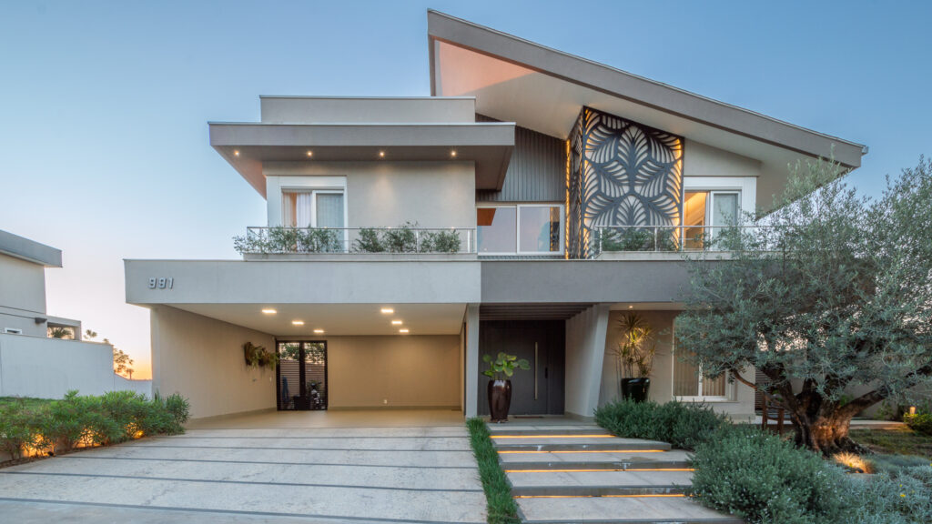 Fachada frontal de residência contemporânea com telhado inclinado, painel vazado iluminado e esquadrias Weiku de perfil branco