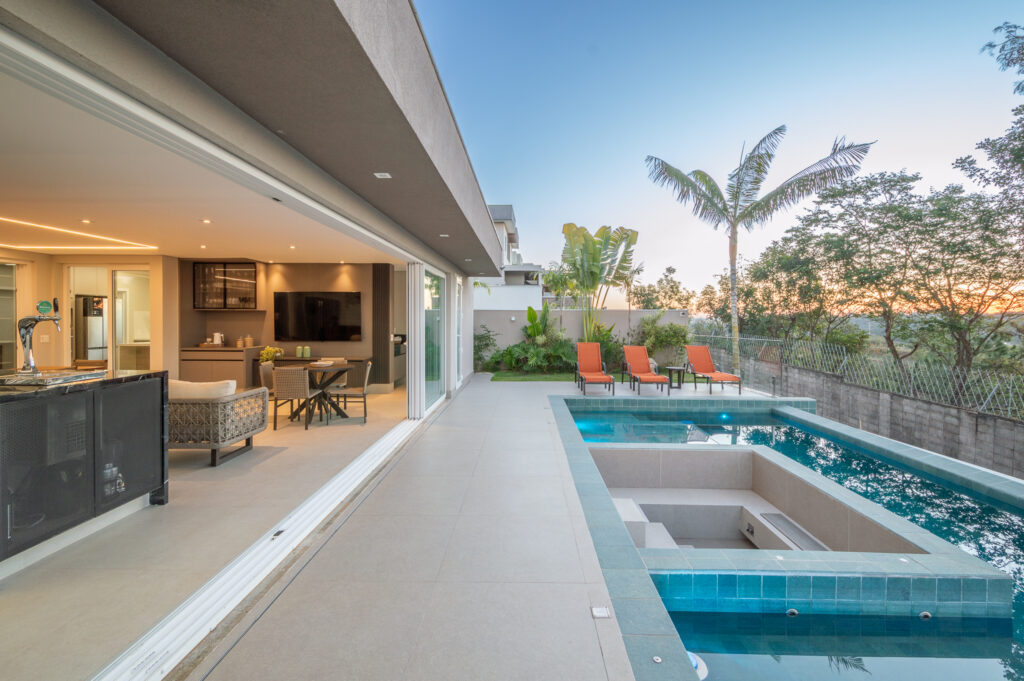 Varanda gourmet integrada à piscina com spa por portas de vidro de correr Weiku de perfil branco totalmente recolhidas