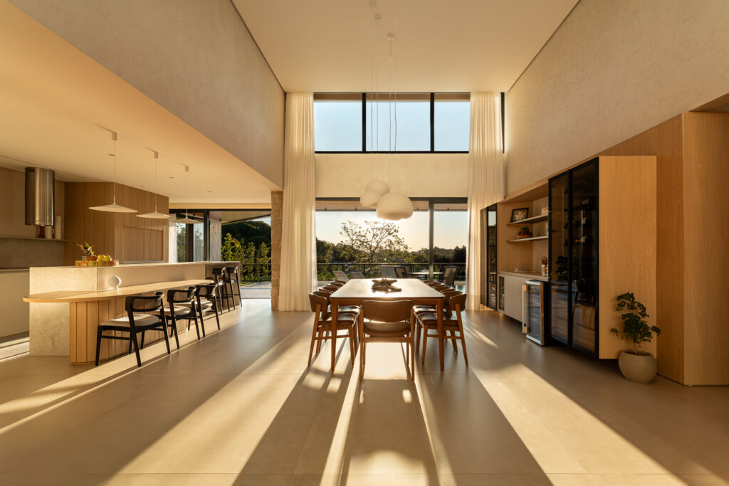 Living, sala de jantar e cozinha integrados sob pé-direito duplo, iluminados por esquadrias de vidro Weiku