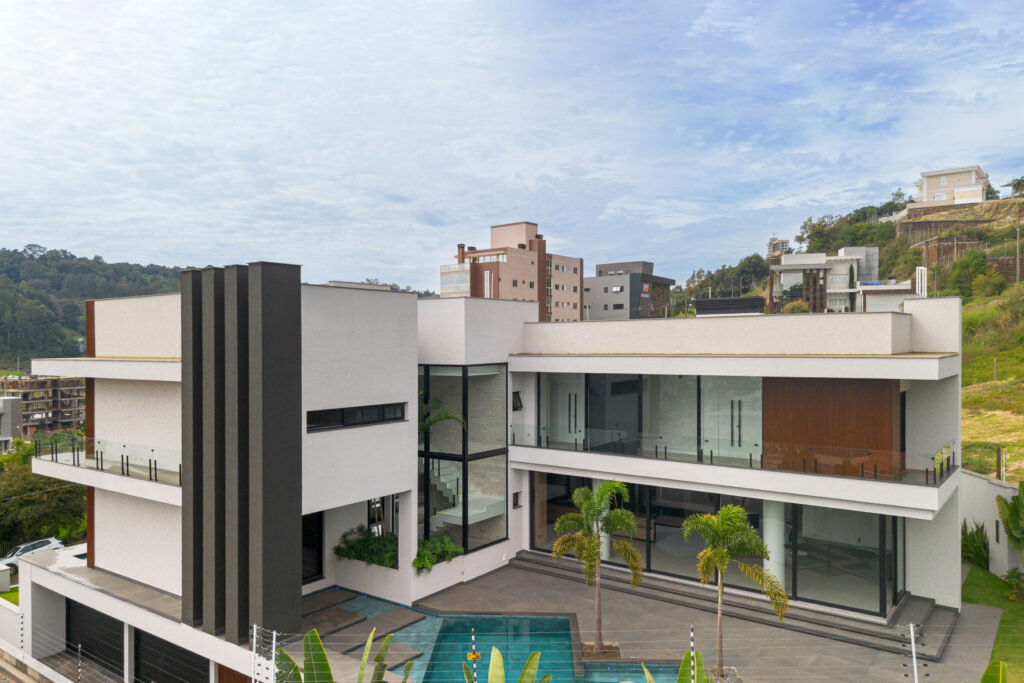 Vista aérea de residência contemporânea com volumes brancos, piscina recortada e panos de vidro Weiku de perfil preto