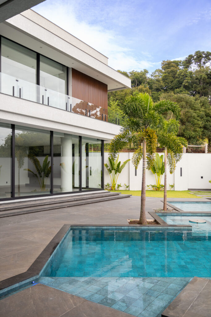 Portas de vidro de correr Weiku de piso a teto voltadas para a piscina com palmeiras, sob sacada de vidro