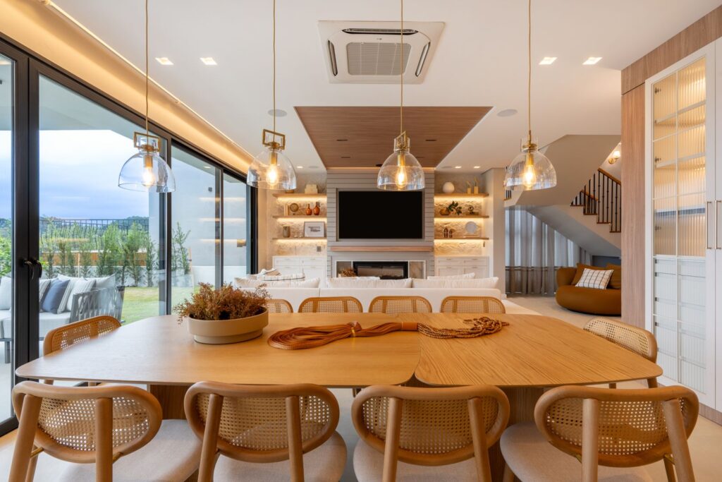 Sala de jantar integrada ao living, com portas de vidro de correr Weiku de perfil preto voltadas para o jardim