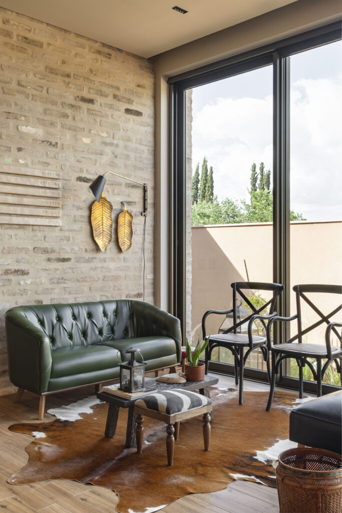 Sala de estar com parede de tijolo aparente, sofá de couro verde e porta de vidro de correr Weiku de piso a teto