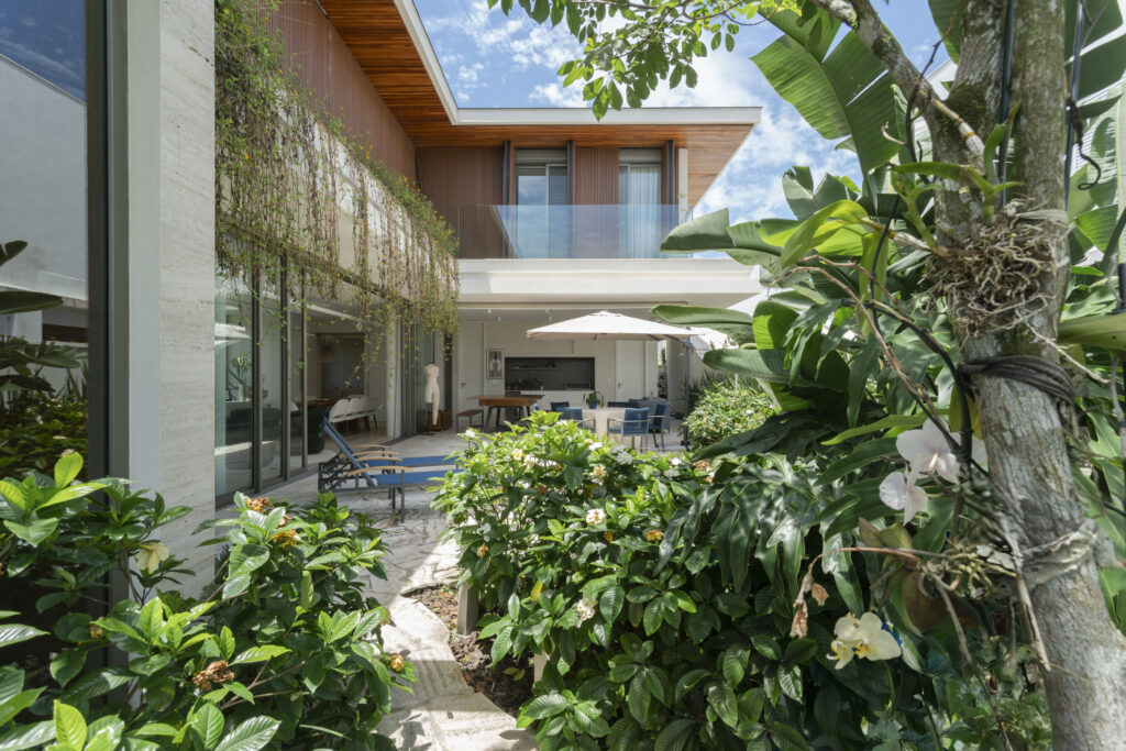 Jardim tropical diante da fachada com panos de vidro Weiku, forro de madeira e sacada com guarda-corpo de vidro