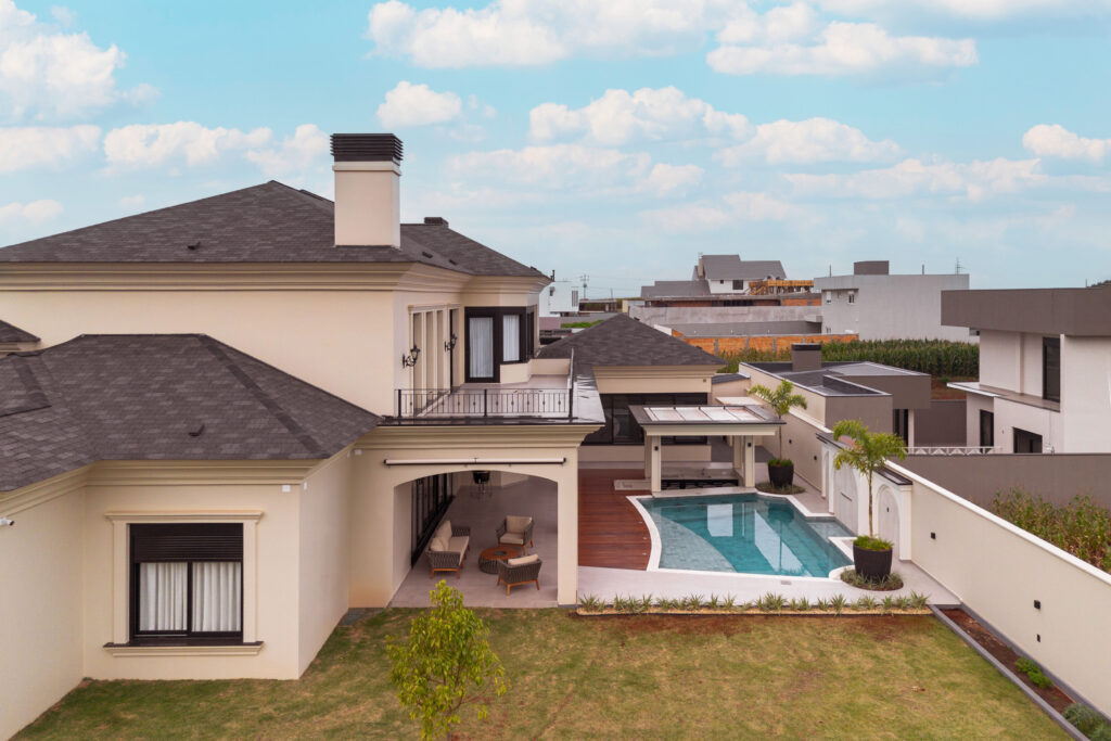 Vista aérea da área externa com piscina, deck de madeira e varanda coberta, com esquadrias Weiku de perfil preto