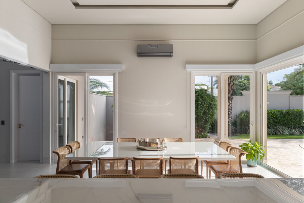 Sala de jantar com portas de vidro e janelas de canto Weiku de perfil branco abertas para o jardim