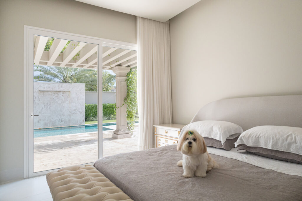 Suíte clara com porta de vidro de correr Weiku de perfil branco voltada para a piscina e o jardim