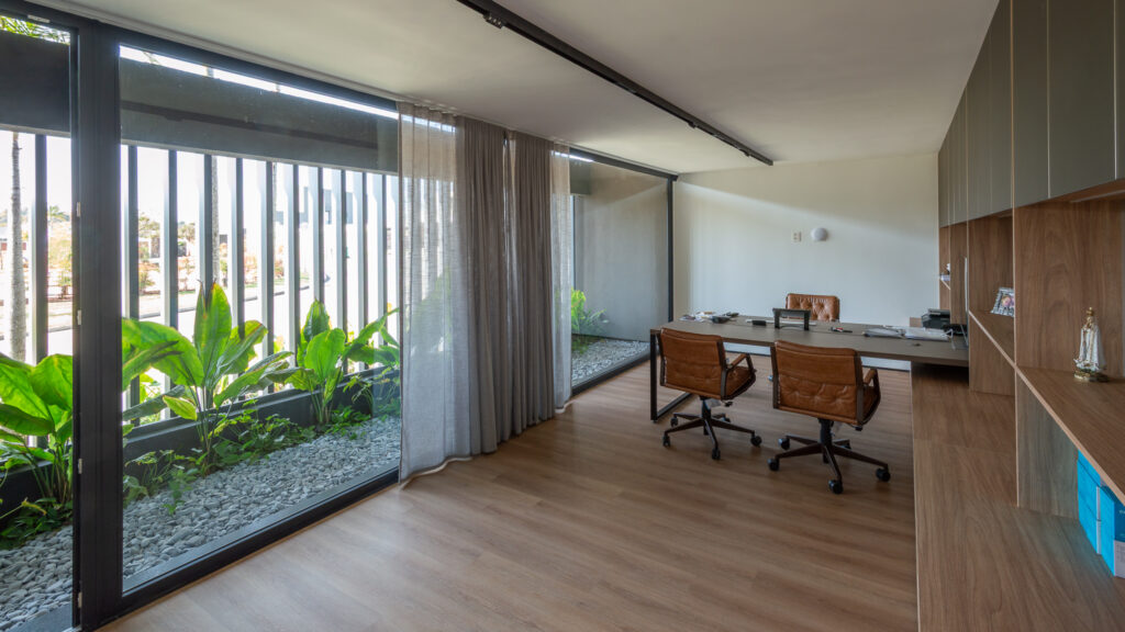 Escritório com panos de vidro Weiku de piso a teto voltados para jardim interno com brises