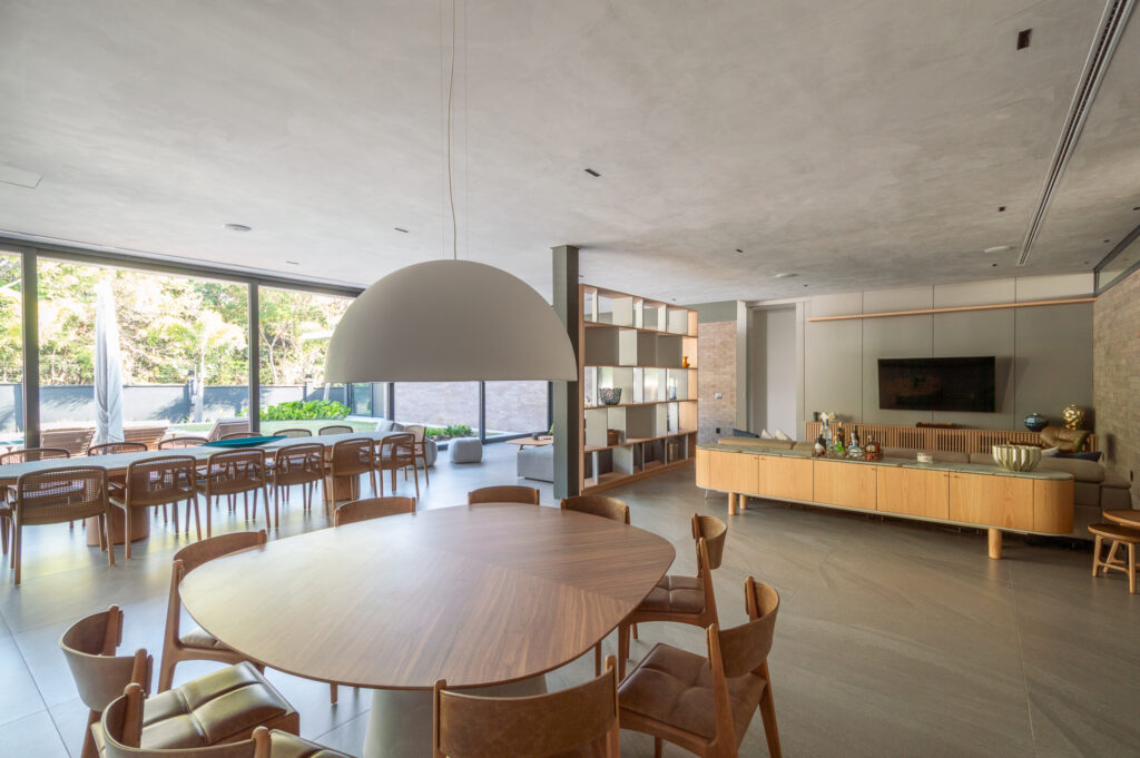 Sala de jantar e living integrados com panos de vidro Weiku de perfil escuro voltados para o jardim