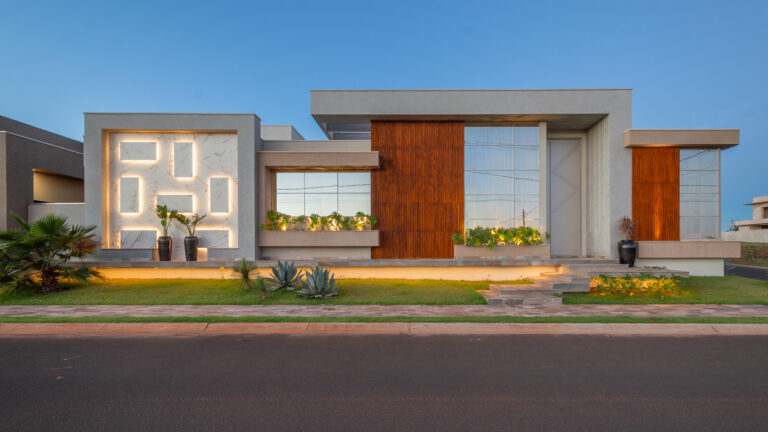 Fachada de residência térrea contemporânea com painel de mármore iluminado, painéis ripados de madeira e panos de vidro Weiku