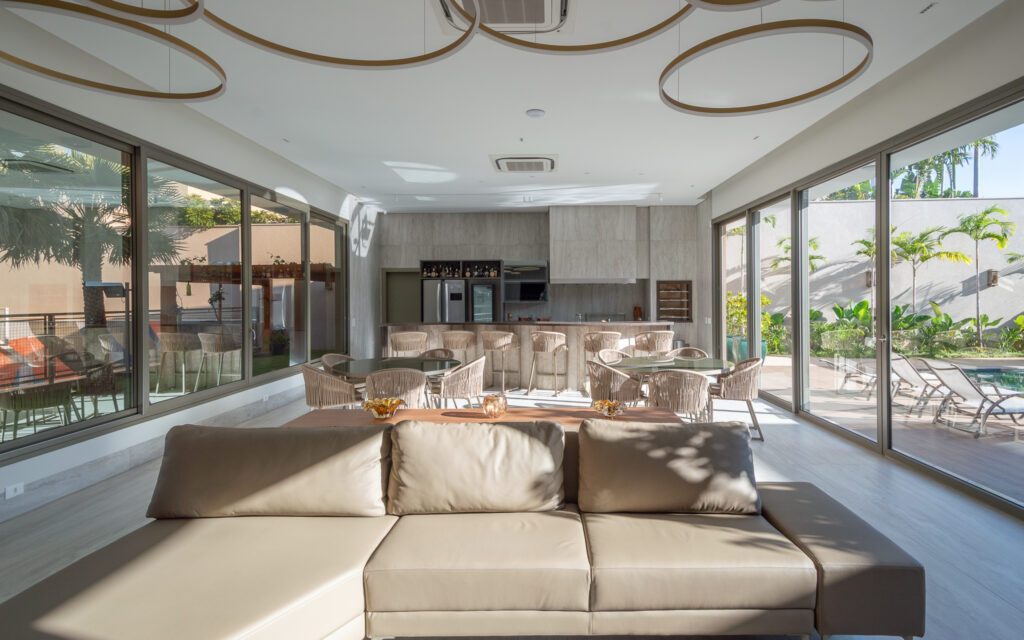 Espaço gourmet com luminárias circulares e panos de vidro Weiku de piso a teto voltados para a piscina e o jardim