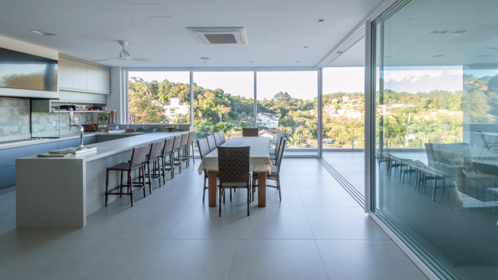 Espaço gourmet com panos de vidro Weiku de piso a teto em canto, emoldurando a paisagem