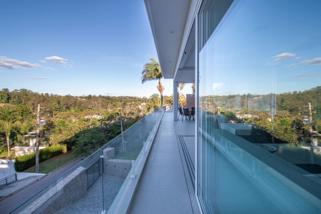 Varanda com guarda-corpo de vidro e panos de vidro Weiku refletindo a vista para a mata